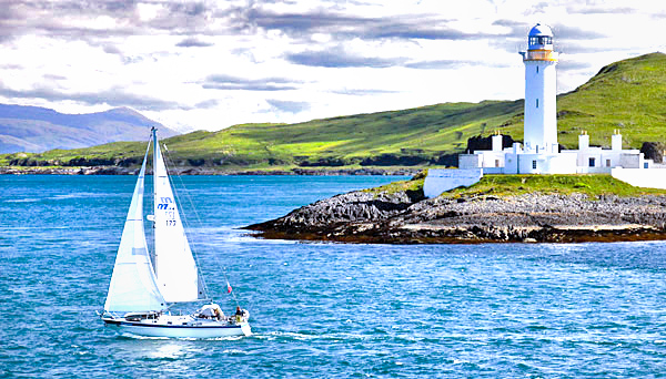 Eilean Musdile lighthouse and yacht, Scotland, UK